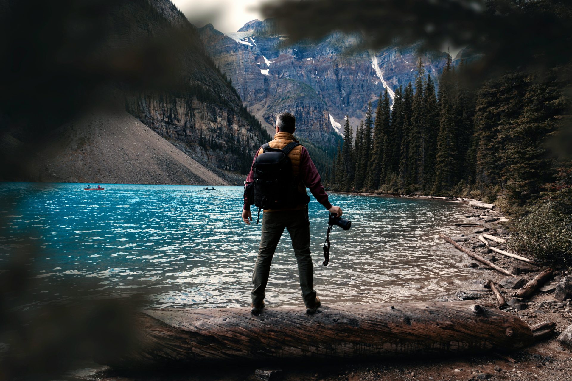 a man standing on a log in front of a lake